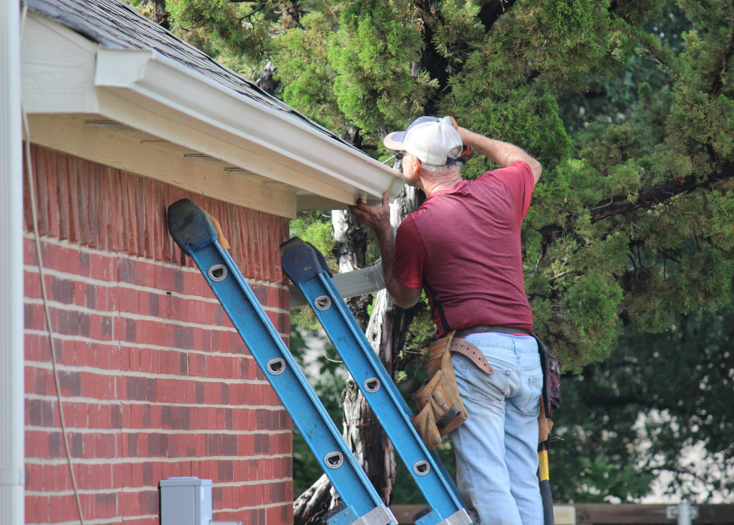 A technician perform emergency roof repair and fixes gutters on a Springdale, AR home.